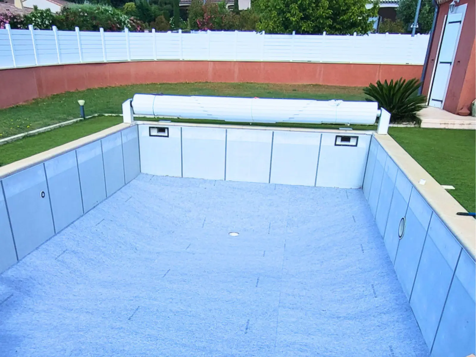 Pose du feutre de protection dans une piscine rénovée avant l’installation du nouveau liner