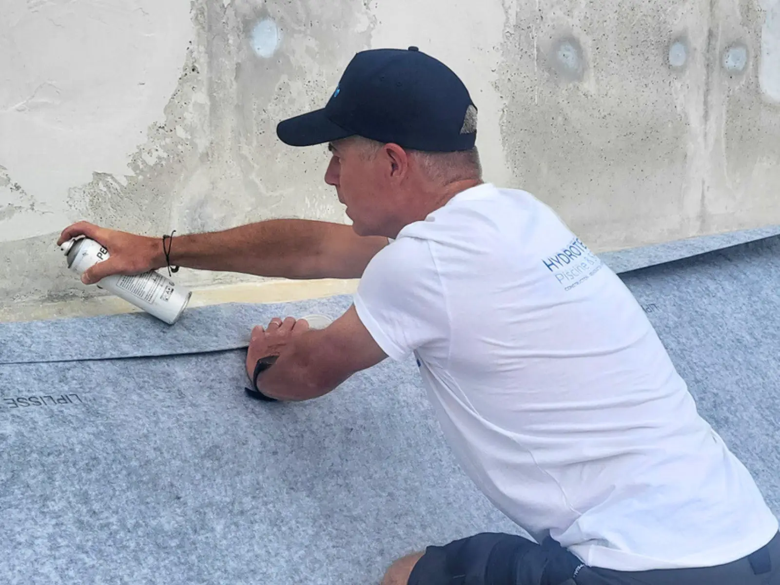 Technicien Hydrotec installant le feutre de protection dans une piscine avant la pose du nouveau liner