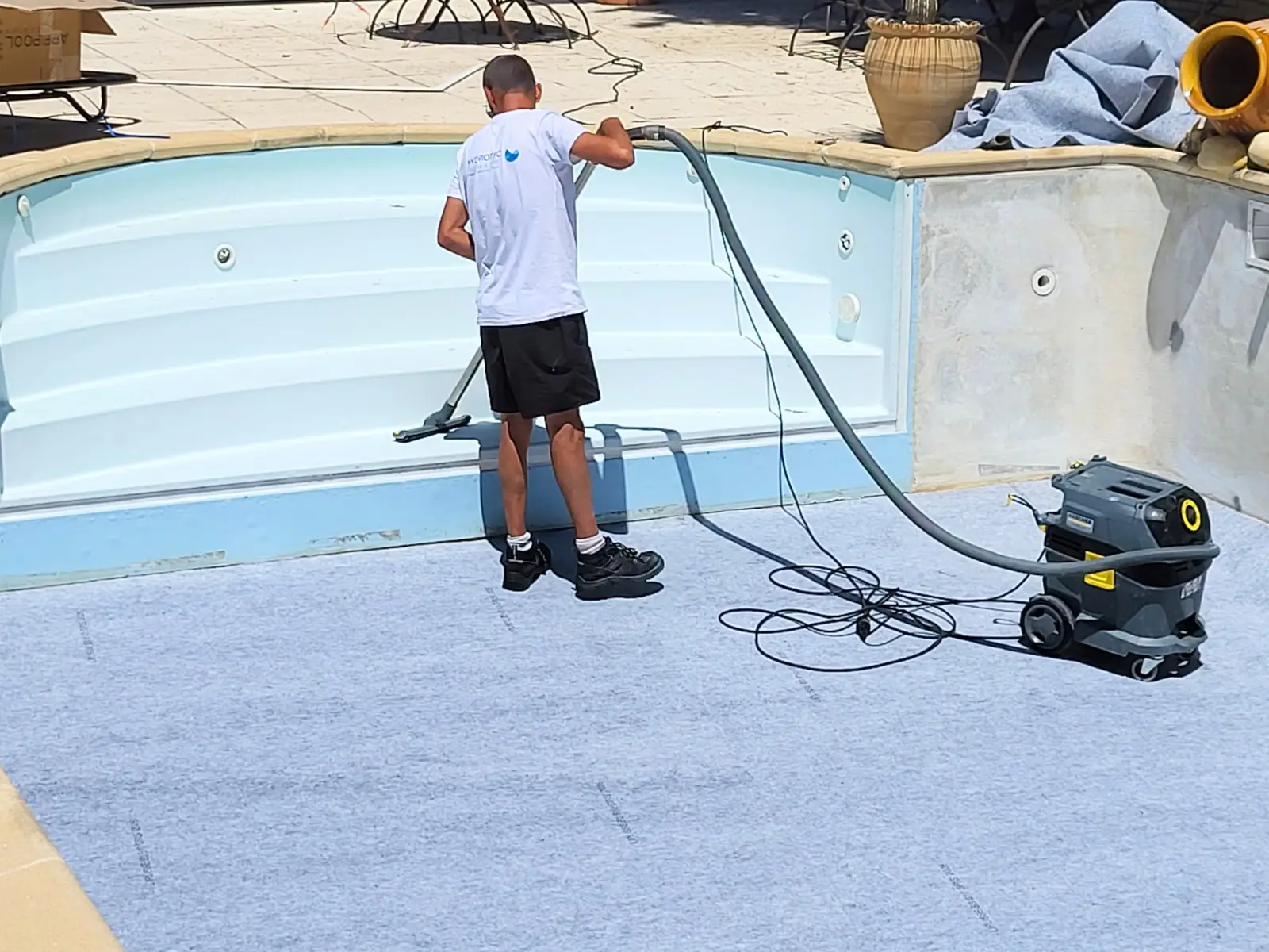Technicien Hydrotec préparant le fond d'une piscine lors d'une rénovation avec pose du feutre de protection