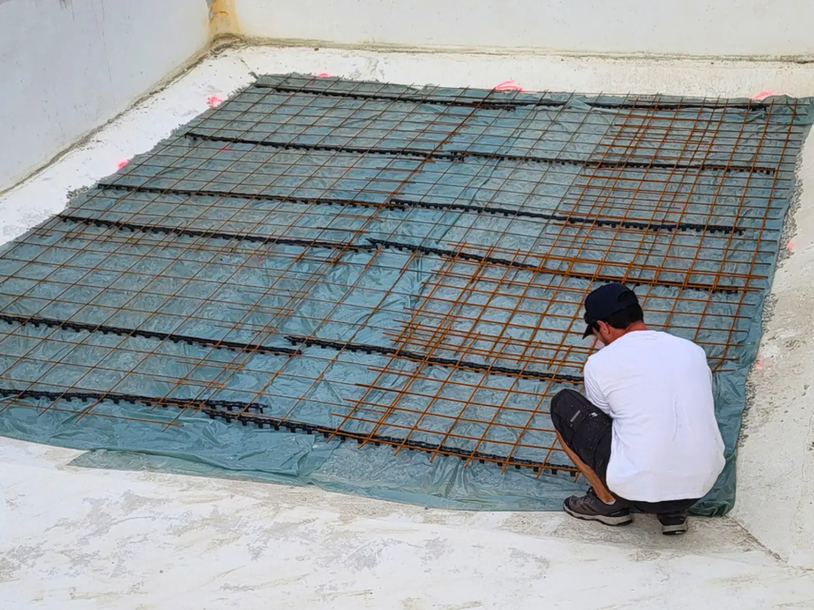 Technicien Hydrotec installant un treillis de renfort sur le fond d’une piscine en rénovation avant reprise de la structure